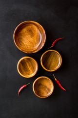 Asian cuisine concept. Wooden bowls and chili pepper on black background top view