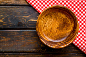 Preparing for lunch - empty wooden bowl closeup on dark wooden background top view copy space