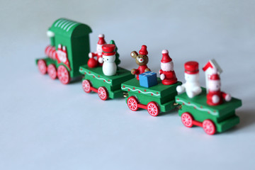 Green festive wooden train riding away on white background with copy space. Selective focus on mouse or rat. Christmas and New Year toy with figures of snowman, gnomes. Greeting card, poster template