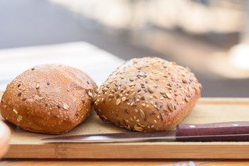Buns with seeds and grain. Fresh rustic crusty bread on wooden board.