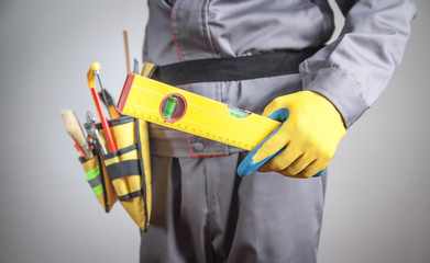 Worker with a tool belt holding level. Construction tools