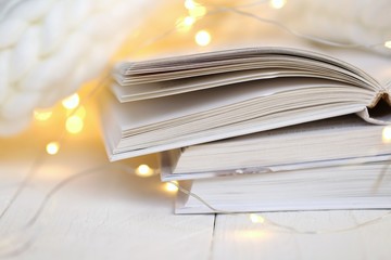 Winter books. Reading in the winter holidays. White cover books close-up, shining garland and white...