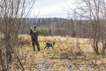 man in camouflage, man, hunter, stands and looks in the field, near a dog, autumn