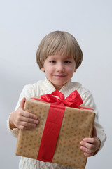 Child holding Christmas gift box in hand. Boy on white background. New year and x-mas concept.