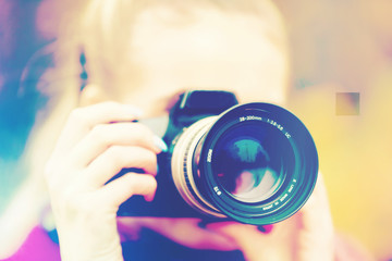 Eine junge Frau fotografiert mit einer Kamera - obrazy, fototapety, plakaty