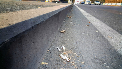 cigarette butts thrown on city highway, concept, need to protect health and nature from pollution.