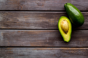 Avocado - whole and halfs - frame on dark wooden background top view copy space