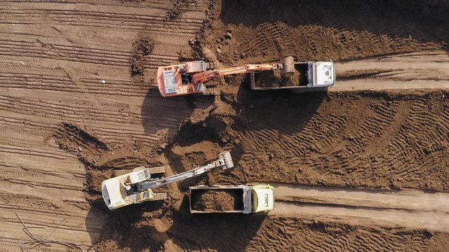 Vast Excavation site with an on going operation of Excavators loading soil onto Trucks, Aerial view.