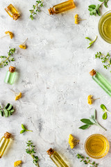 Natural wellness. Essential oils near herbs and leaves on grey background top view pattern frame copy space