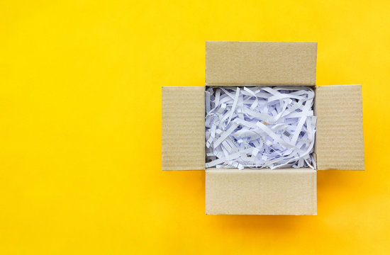 top view reuse shredded paper documents in brown paper cardboard isolated on yellow background with copy space, flat lay