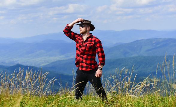 future. cowboy in hat outdoor. man on mountain landscape. camping and hiking. travelling adventure. hipster fashion. countryside concept. farmer on rancho. sexy macho man in checkered shirt
