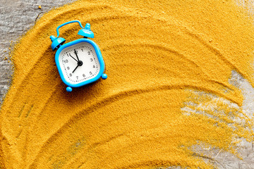 Waste of time concept. Clock on sand on grey background top-down copy space