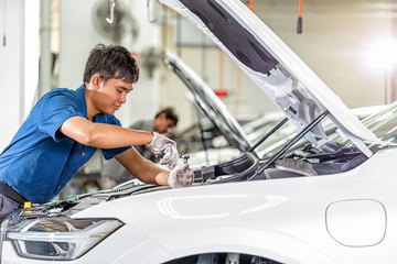 Asian mechanic Checking and repairing the car in maintainance service center which is a part of...