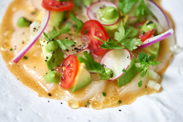Tartar from scallop with avocado, cherry tomatoes, radishes and onion. Dish in the restaurant from raw seafood.
