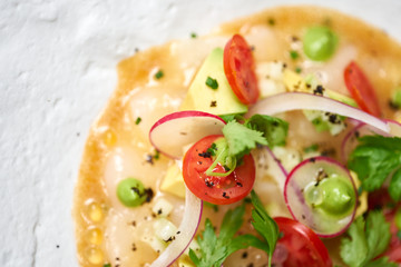 Tartar from scallop with avocado, cherry tomatoes, radishes and onion. Dish in the restaurant from raw seafood.
