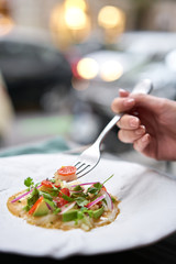 Lunch in a restaurant, a woman eat Tartar from scallop with avocado, cherry tomatoes, radishes and onion. Dish in the restaurant from raw seafood.