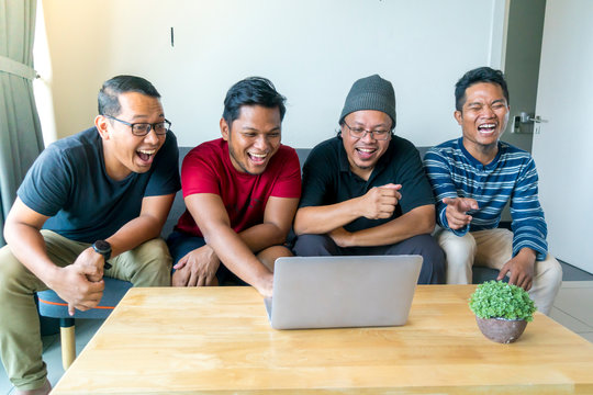 Asian Malay Friends At Apartment Watching Movie At Laptop Together