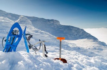 Equipment for mountaineering on the top of a snow-capped mountain on the background of the sun....