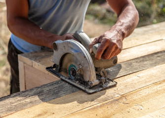 A worker cuts a wooden beam at a construction site