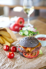 Cheeseburger with lettuce, tomato, fries, and melted cheese. The table in the restaurant. Unhealthy food.