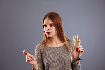Attractive cheerful lovely girl with long light hair smiling, holding Bengal light and drinking...