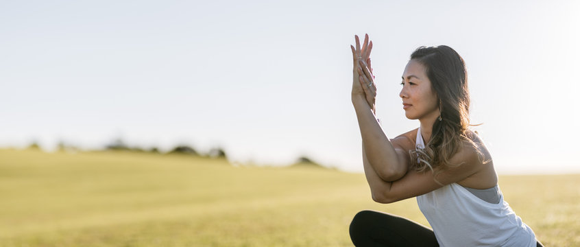 Calm young woman doing yoga in grassy field