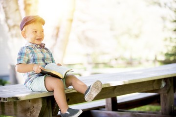 Closeup shot of a child happy child with an open bible on his laps and a blurred background