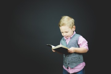 Closeup shot of a child reading a bible with a black background