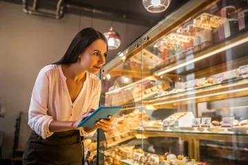 Tuinposter Businesswoman holding tablet while ordering foods for bakery © zinkevych