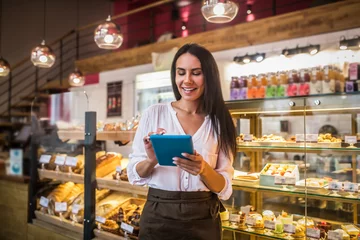 Fotobehang Bakkerij Cheerful young businesswoman ordering foods for her bakery  © zinkevych