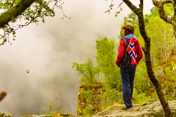 Tourist with norwegian flag in hazy mountains