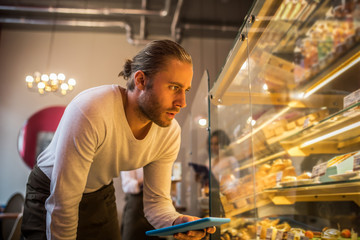 Businessman holding tablet while ordering pastry for bakery