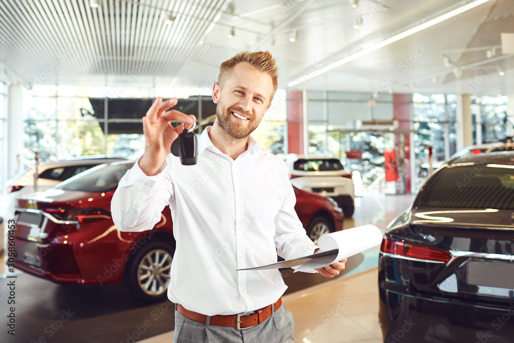 Wall mural A car dealer standing in a showroom.