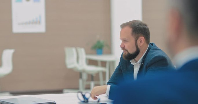 Business meeting of young businessmen in a coworking center, discussion of company business ideas. Circular motion of the camera.