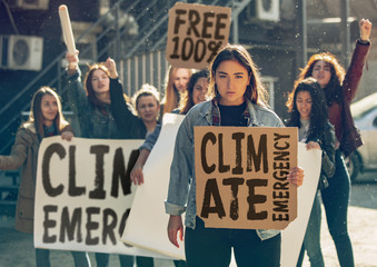 Young woman with poster in front of people protesting about climate changing on the street. Meeting...