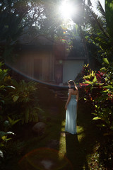 Young girl in a turquoise dress in the sunshine among tropical greenery, Bali, Indonesia