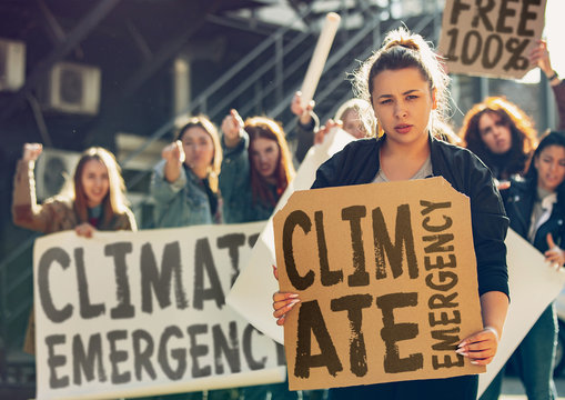 Young Woman With Poster In Front Of People Protesting About Climate Changing On The Street. Meeting About Problem In Ecology, Environment, Global Warming, Industrial Influence, Climate Emergency.