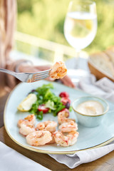 Grilled Argentine shrimp with mango-jalapeno sauce. Lunch in a restaurant, a woman eats delicious and healthy food. Delicious fresh seafood prawns with fresh vegetables and lime. Cream sauce