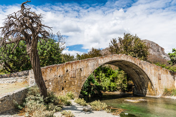 Fototapeta na wymiar The stream under the arch of the stone bridge