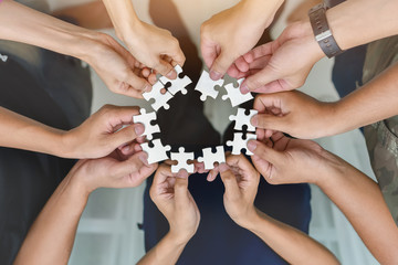 The hands of a multi-national team that assembled jigsaw puzzles Working on successful teamwork concepts, helping and supporting businesses in the near term.