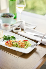Closeup of salted and smoked salmon or trout fillet on a fork. Salmon tartare with cucumber and sesame seeds. Tasting dish on a wooden table.