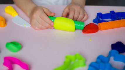 Child hands playing with colorful clay. Homemade plastiline. Girl molding modeling clay. Homemade clay. Child playing and creating from play dough.