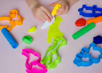 Child hands playing with colorful clay. Homemade plastiline. Girl molding modeling clay. Homemade clay. Child playing and creating from play dough.