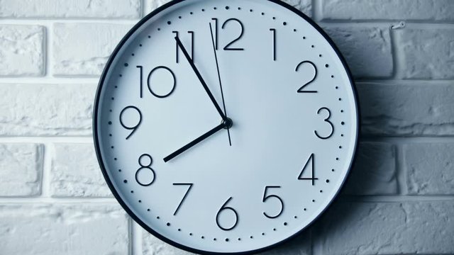 Single white clock hanging on a brick wall