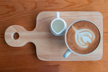 Latte coffee cup with latte art on wooden table in coffee shop.