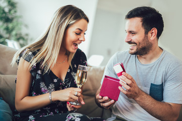 Young man giving a surprise gift to woman in the living room at home