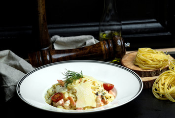 seafood fettuccini with creamy sauce, parmesan topped with cherry tomato and dill