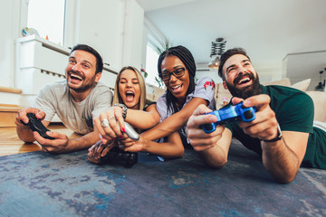 Happy multiethnic friends playing video game and having fun at home.