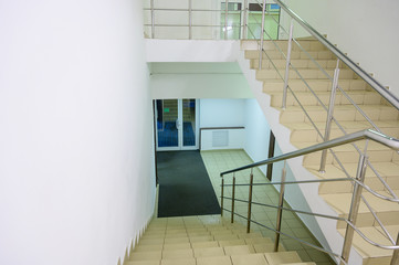 The concept of the interior of an urban building. Photo of a staircase with metal railing between floors.