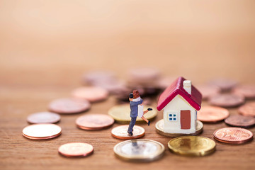 miniature couple stand on stack coins with tiny home and piggy bank ,  Image for real-estate and saving money management  concept.